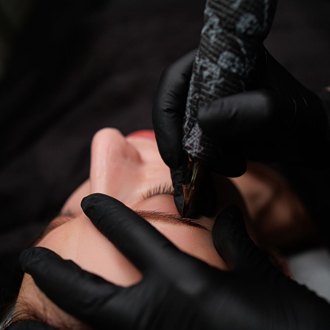 Gloved hands working with a cosmetic tattoo pen